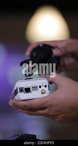 A vertical closeup of a male technician's hand  repairing a CCTV camera in the service center Stock Photo