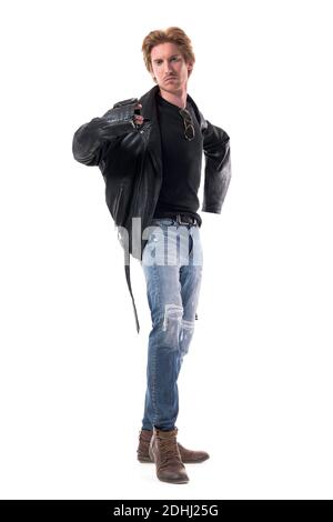 Cool confident young man getting dressed put on black leather jacket looking at camera. Full body length isolated on white background. Stock Photo