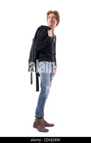 Side view of handsome male fashion model in jeans carrying leather jacket on shoulder look back. Full body length isolated on white background. Stock Photo