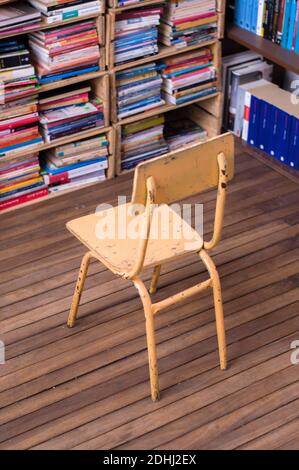 A high angle view of a small metal old chair on a wooden floor with library book details Stock Photo