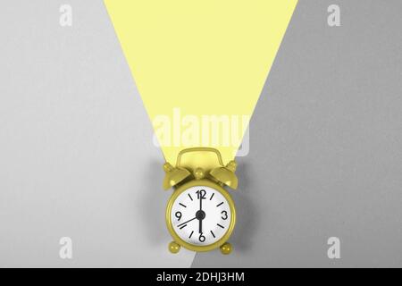 Classic analogue alarm clock on illuminating yellow and gray ultimate tone background as a concept of color trend of the year 2021. Stock Photo