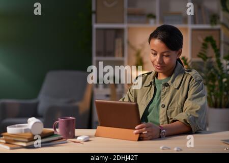 Young serious businesswoman concentrating on her online work at the table she using digital tablet at office Stock Photo