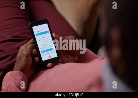 Close-up of African man lying on sofa and using online calendar on his mobile phone he looking at his tasks Stock Photo