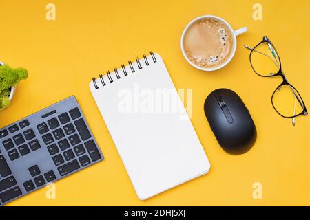 Keyboard, computer mouse and cofffe on yellow background, top view Stock Photo