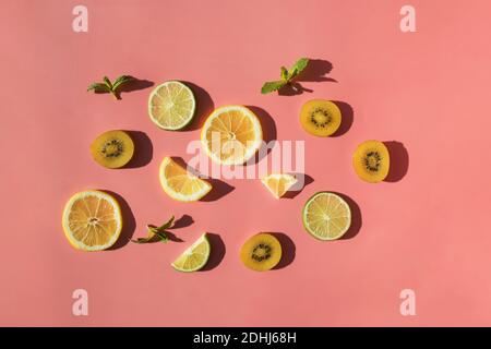 Flat lay of Sliced fruits on pink bacjground with natural sunlight hard shadows. Trendy summer template. Stock Photo