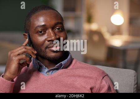 Portrait of African handsome man looking at camera while has a conversation on mobile phone Stock Photo