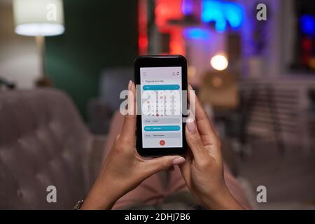 Close-up of woman holding mobile phone and using online calendar at home Stock Photo
