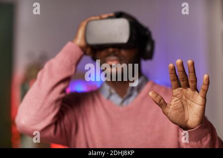 African man in virtual reality glasses gesturing while playing online game Stock Photo