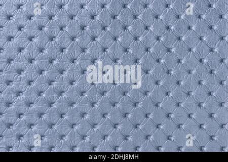Texture of light blue leather background with capitone pattern, macro. Denim textile of retro Chesterfield style. Vintage fabric backdrop. Stock Photo