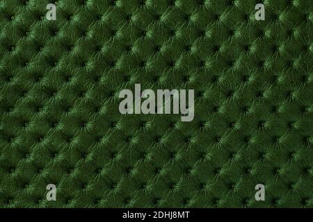 Texture of dark green leather background with capitone pattern, macro. Emerald textile of retro Chesterfield style. Vintage fabric olive backdrop. Stock Photo