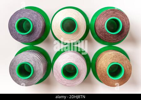 Set of big bobbin and skeins of thread different colors on white background, closeup. Materials for creativity and industry sewing. Stock Photo