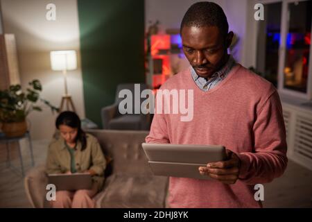 African young man using digital tablet while standing at office with woman in the background Stock Photo