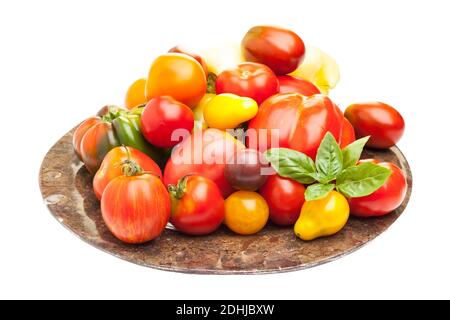 Many different kinds of tomatoes on plate against white background Stock Photo