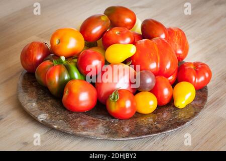 Colorful tomatoes on plate on wooden table Stock Photo