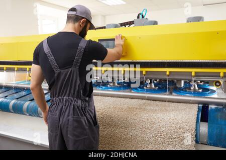 Man operating carpet automatic washing machine in professional laundry service Stock Photo