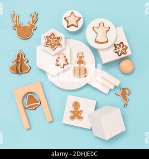Christmas composition with gingerbread cookies in trendy minimalistic style. Different geometrical shapes, podiums and christmas cookies, flat lay or top view. Christmas baking on blue background Stock Photo