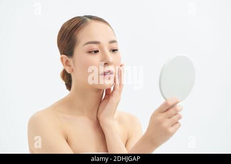 Shot of a beautiful young woman looking at herself in small mirror over white isolated background. Stock Photo