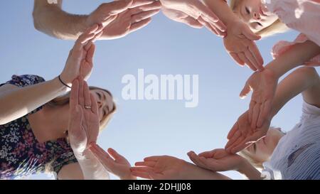A friendly family makes a circle out of their hands and looks into it. Stock Photo