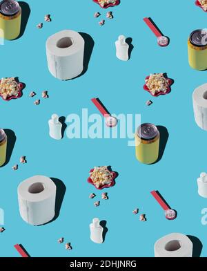 From above of patterns of hygiene supplies and soda cans on blue background with popcorn Stock Photo