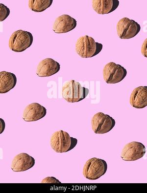 From above of brown walnuts arranged in rows on pink background in studio Stock Photo