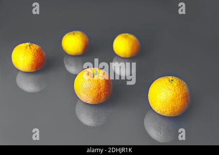 Composition with bright illuminating yellow tangerines on a gray color background. Pattern, copy space. Concept of Color of the Year 2021. Stock Photo