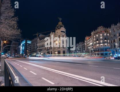 Famous Metropolis Building located near road illuminated by blurred traffic light trails in Madrid Stock Photo