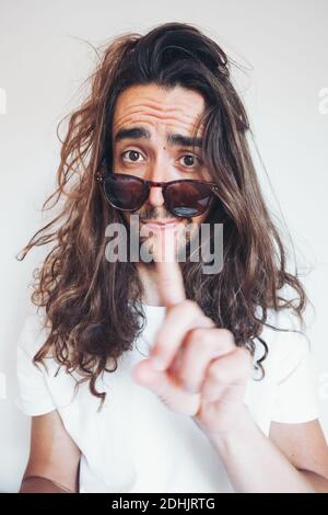 Young hipster long haired bearded male in sunglasses with funny amazed face expression looking at camera while taking selfie Stock Photo