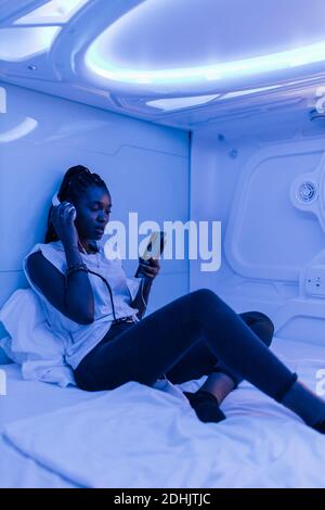 Excited Latin male with Afro hairstyle and in VR goggles experiencing virtual reality on black background in studio with neon lights Stock Photo