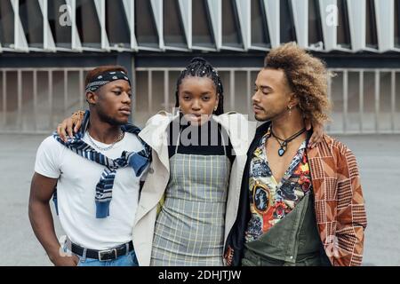 Group of serious unemotional young African American hipster friends in trendy outfits on urban street Stock Photo