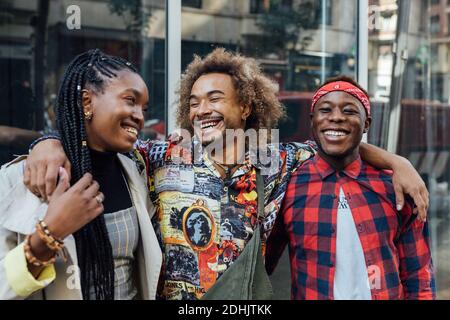 Group of cheerful young African American hipster friends in trendy outfits smiling happily on urban street Stock Photo