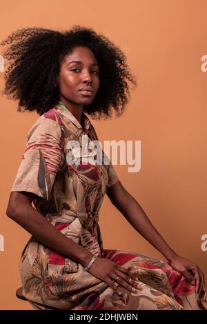 Serious African American model with Afro hairstyle looking at camera on brown studio background Stock Photo