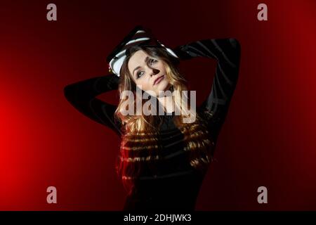 Young blonde Woman wearing virtual reality headset standing on colorful red studio background looking away Stock Photo