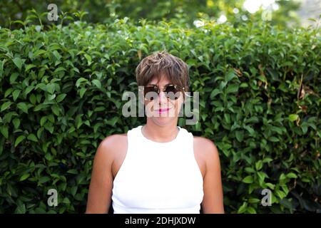 Content adult female with short hair and in trendy outfit standing in green park in summer and looking at camera Stock Photo