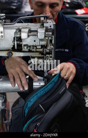 Male worker is repairing luggage with sewing machine at workshop in Santiago , Chile Stock Photo