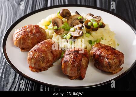 Slavink is a traditional Dutch dish consisting of meat that is wrapped in bacon and fried served with mashed potatoes and mushrooms closeup in the pla Stock Photo