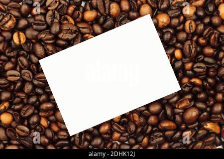 Coffee beans are scattered over the surface on a blank white background. a handful of brown coffee beans. Coffee background with copy space for Stock Photo