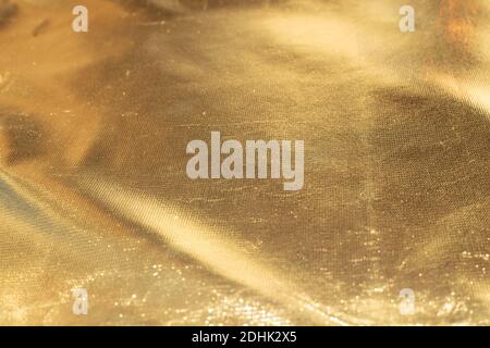 Golden sparkling Christmas background. Crumpled fabric texture, soft focus. Stock Photo