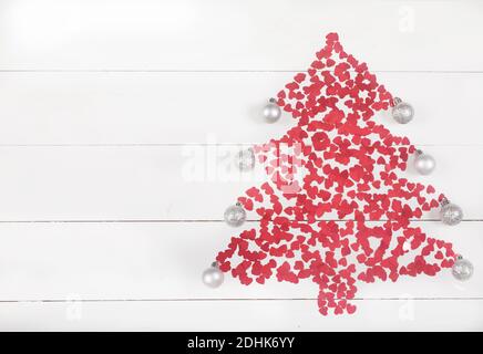 Red hearts are laid out in the shape of a Christmas tree with balls on a white wooden background. Holiday concept Stock Photo