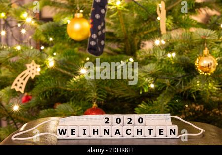 Symbol for the Christmas time during the corona pandemic. Dice form the German expression 'Weihnachten 2020' (Christmas 2020) on top of a face mask in Stock Photo