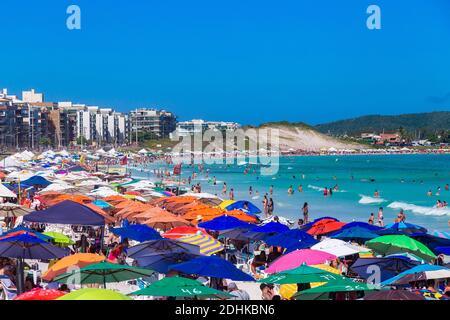 CABO FRIO, RIO DE JANEIRO, BRAZIL - DECEMBER 26, 2019: Panoramic view of Praia do Forte beach. Many colorful parasols and people enjoying the water an Stock Photo