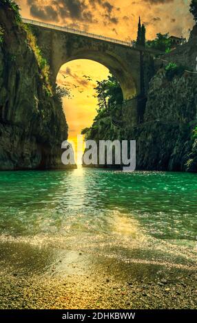 Fiordo di Furore, Amalfi coast picturesque golden hour sunset seascape scenic view on arched bridge between high rocks and stone beach. Italy Stock Photo