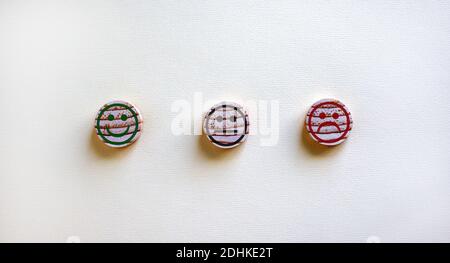 Quality and feedback symbol. Various emoticons made of wooden circles drawn lines of a mouth. Over white background in a conceptual image of quality a Stock Photo