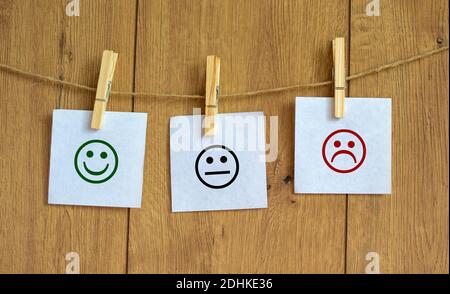 Quality and feedback symbol. Various emoticons made of paper drawn lines of a mouth. Over wooden background in a conceptual image of quality and feedb Stock Photo