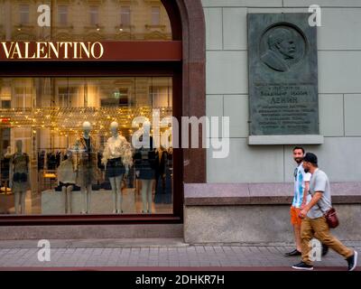An Argentinian football fan walks past a monument to Lenin located next to a fashion outlet.  Vladimir Ilyich Ulyanov, better known by the alias Lenin Stock Photo