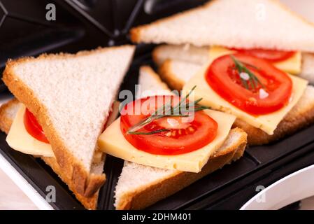 Making Cheese and Tomato Sandwiches on a Sandwich Press. Stock Photo