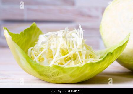 Fresh white cabbage and fresh cabbage salad with carrots with original serving on a cabbage leaf. Stock Photo