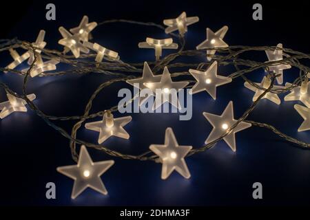 Decoration stars glowing on dark blue background. Christmas and New Year background. Stock Photo