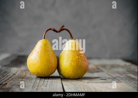 https://l450v.alamy.com/450v/2dhmamf/a-couple-of-fresh-yellow-ripe-organic-yellow-pears-form-the-shape-of-the-heart-on-rustic-wooden-table-on-the-gray-stone-background-relations-love-2dhmamf.jpg