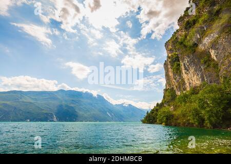 Nature wilderness landscape at lake Garda, Italy on a beautiful summer day. Blue water, rocks, mountains, sunlight and clear sky. Stock Photo