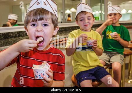 Alabama Sylacauga Blue Bell Creameries ice cream manufacturing plant production,children boys eating ice cream tour school field trip students,wearing Stock Photo